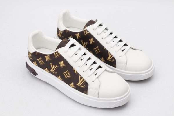 A pair of low-top sneakers with a brown and gold monogram pattern on the sides and white leather on the toe